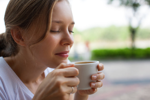 漂亮女人在户外闻咖啡的特写图片下载