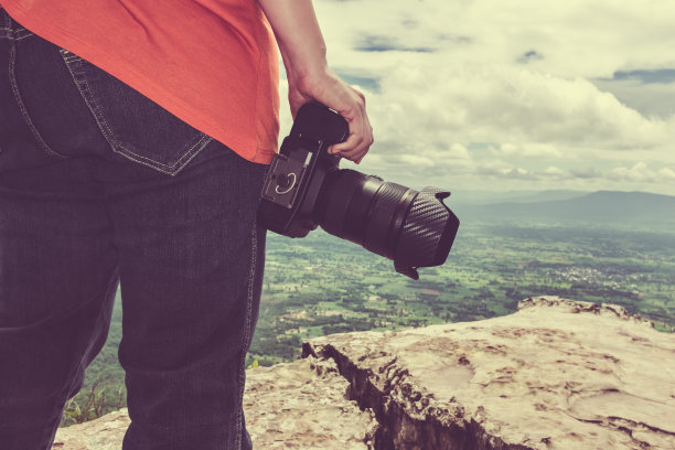 带着数码相机的女人站在山上。旅游生活方式度假概念图片下载