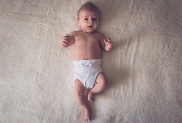 婴儿躺在舒适的白色毯子上图片下载