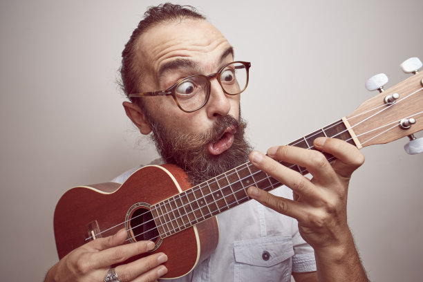 一个年轻人用滑稽的表情弹奏着四弦琴图片下载