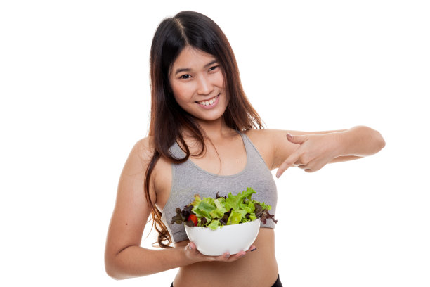 美丽的亚洲健康女孩指着沙拉。图片下载