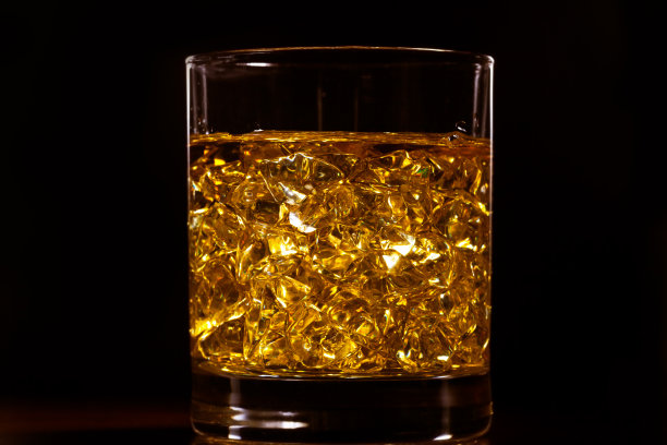 木桌上放着金色烈性酒和冰块图片下载