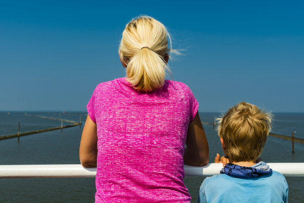 一个女人和一个男孩站在岸边，望着大海图片下载