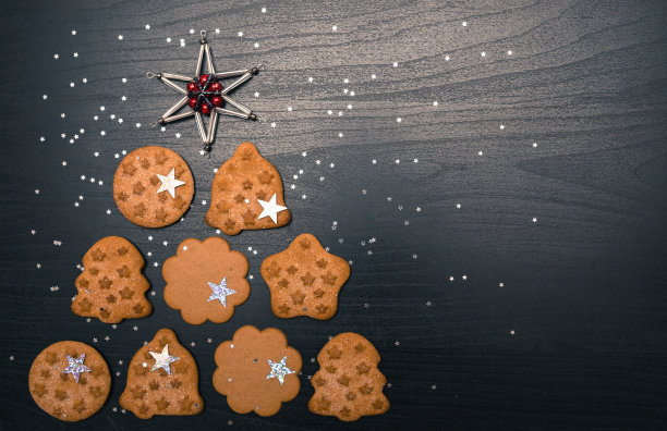 用姜饼做的圣诞树，在黑色的背景上顶部有星星。新年和圣诞节的明信片图片下载