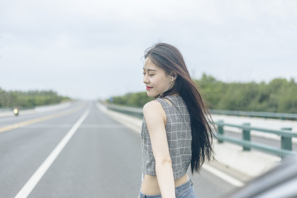 漂亮女人靠在引擎盖上，听着音乐图片下载