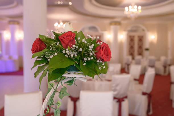 节日餐桌上的装饰有大的红玫瑰，婴儿呼吸花和绿色植物图片下载