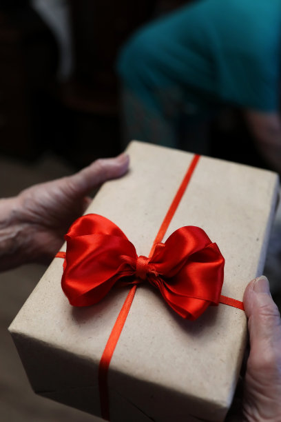 祖母手里拿着红色蝴蝶结的礼盒图片下载