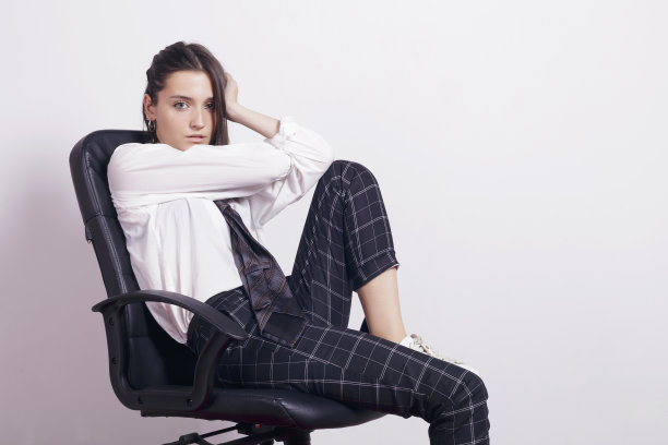 女孩穿着校服，坐在办公室的椅子上。图片下载