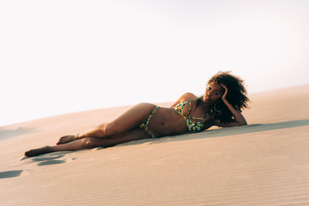 美丽的年轻女子在沙丘的沙子上摆姿势图片下载