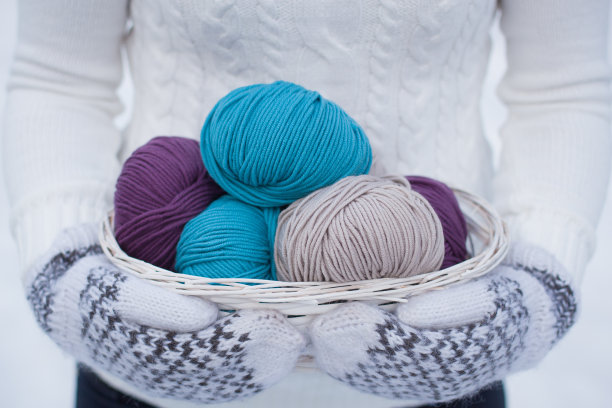 毛线装在白色的篮子里。白色和棕色针织羊毛连指手套。图片下载
