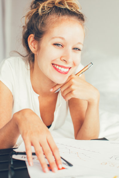 微笑的商务女士在床上处理文件图片下载