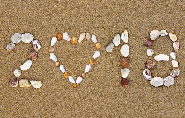 卵石新年2018年数字与贝壳心形在潮湿的沙滩上。2018年夏季假期概念。图片下载