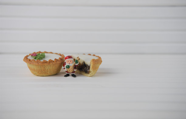 圣诞美食照片与肉馅饼和迷你圣诞老人与乐器和白木背景图片下载
