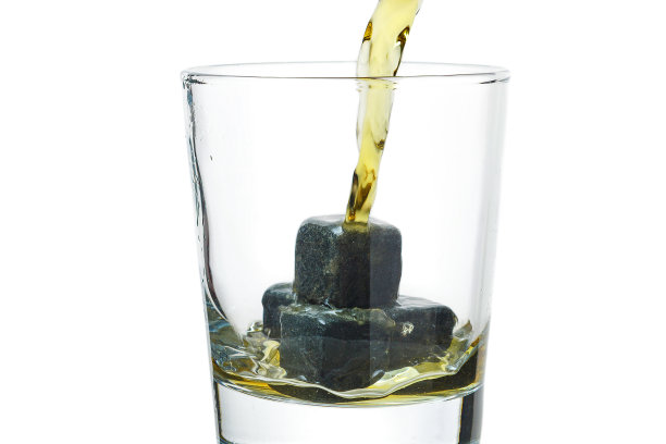 威士忌倒进装有石头的玻璃杯里。图片下载