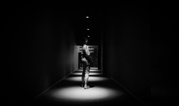 女人独自走在一个空的黑暗走廊在公寓大楼透视与复印空间。图片下载