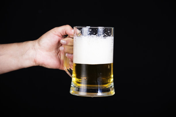 手拿着一品脱啤酒黑色背景和一个大泡沫头图片下载
