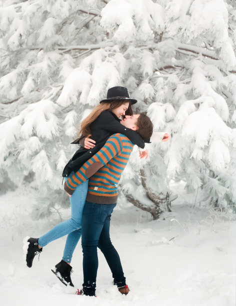 幸福的年轻情侣在冬天的雪地里接吻。冬天的爱情故事。图片下载