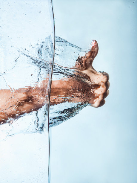 女人拳头穿过蓝色的水和溅水花图片下载