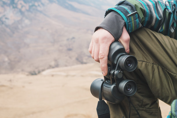 一个在山里的旅行者手里拿着一个大望远镜图片下载
