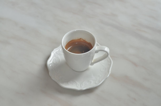 白色大理石桌上的咖啡杯(表面有花朵图案)。图片下载