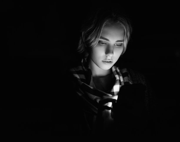 晚上用智能手机的女人。图片下载