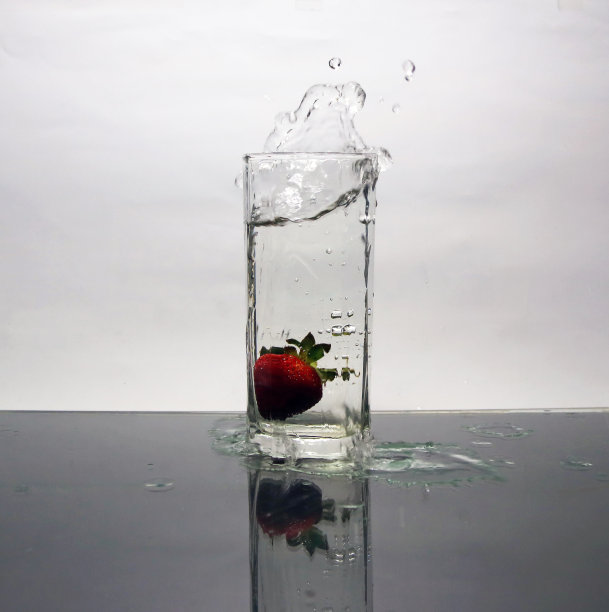 落下的草莓和溅水在玻璃上的白色背景。图片下载