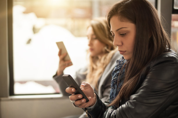 一个年轻女孩在城市公共汽车上使用手机图片下载