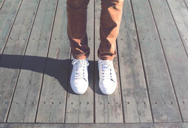 时尚潮酷的人与白色运动鞋近距离站在木地板上图片下载