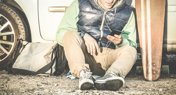 年轻男子在车旁用手机听音乐图片下载