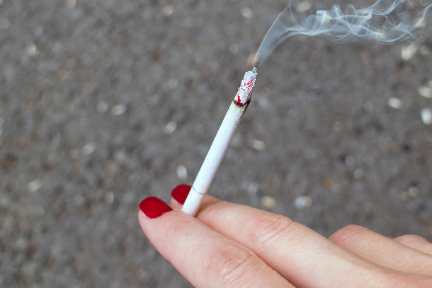 一个女人的手上涂着指甲，正在冒烟的香烟图片下载