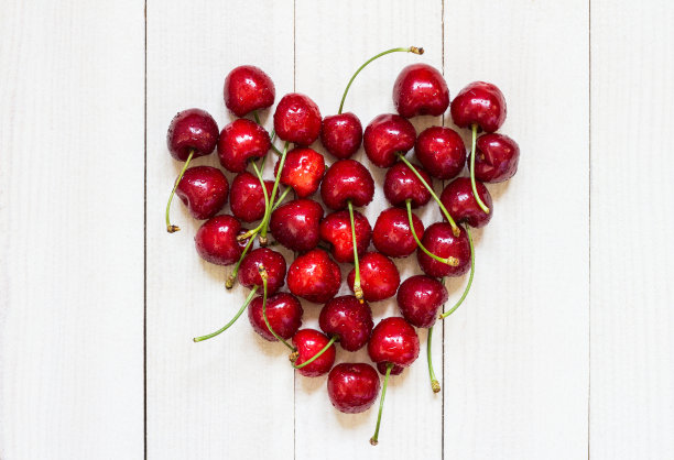 白色木质背景上的心形红樱桃图片下载