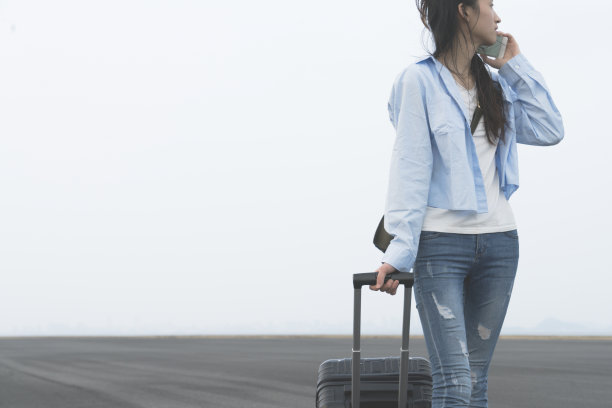 年轻女子拿着行李箱走路，用手机打电话图片下载
