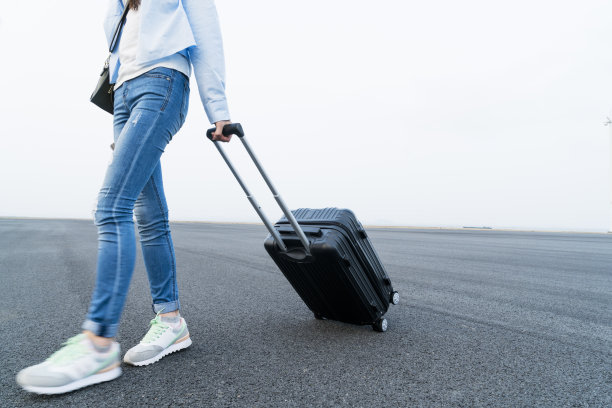 一个年轻女子拖着箱子在天空下走图片下载