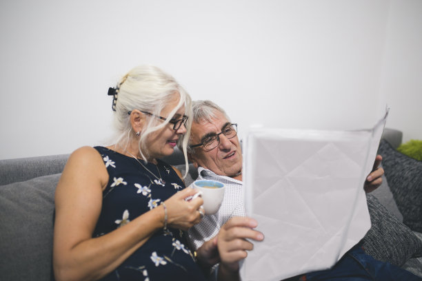 一对老年夫妇在家看报纸，在沙发上休息图片下载