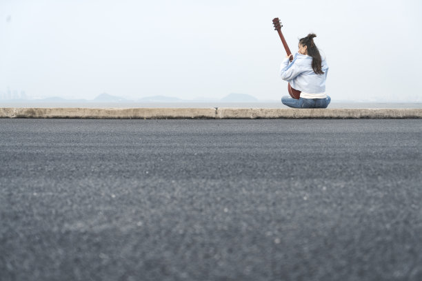 年轻女子坐在河边弹吉他图片下载