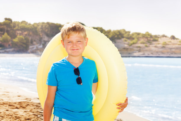 海滩上戴着充气戒指的男孩图片下载
