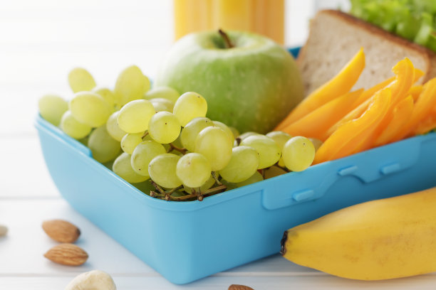 白色木制背景上的健康零食午餐盒。图片下载