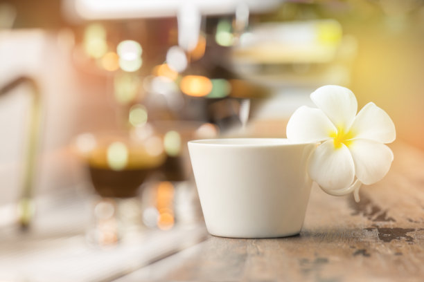 在放着鸡蛋花的旧木桌上放着一杯咖啡图片下载