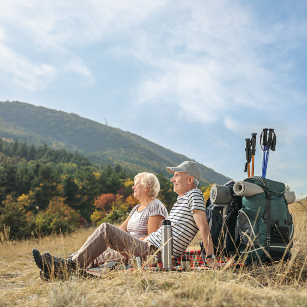 老徒步旅行者坐在毯子上看向别处图片下载