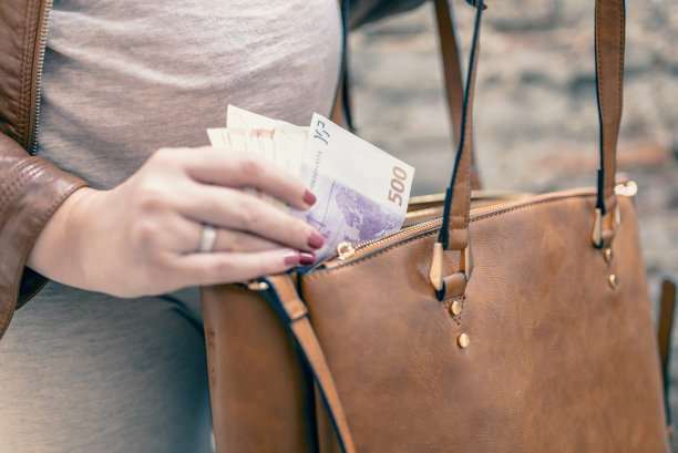 特写照片时尚的女人把钱从袋子里拿出来。漂亮的女人的手指拿着钱和钱包。女人把钱从包里拿出来。花钱。女人准备付钱图片下载