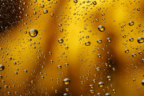 冰冷的玻璃覆盖着水滴凝结冷饮水滴金色的黄色-橙色的饮料背景雨点纹理近图片下载