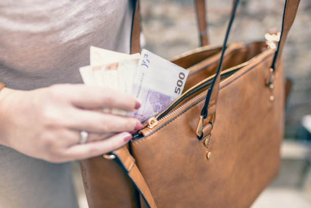 特写照片时尚的女人把钱从袋子里拿出来。漂亮的女人的手指拿着钱和钱包。女人把钱从包里拿出来。花钱。女人准备付钱图片下载
