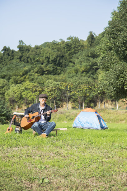 年轻人在草坪上弹奏乐器图片下载