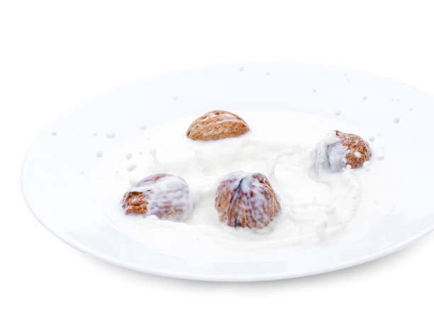 核桃和牛奶一起落在白色的碗里。白色背景上的孤立照片。一滴牛奶。冻结的时间图片下载