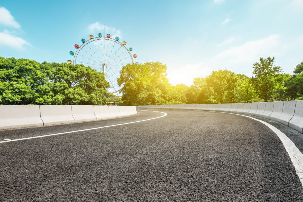 柏油路和摩天轮游乐场，城市公园里有绿树图片下载