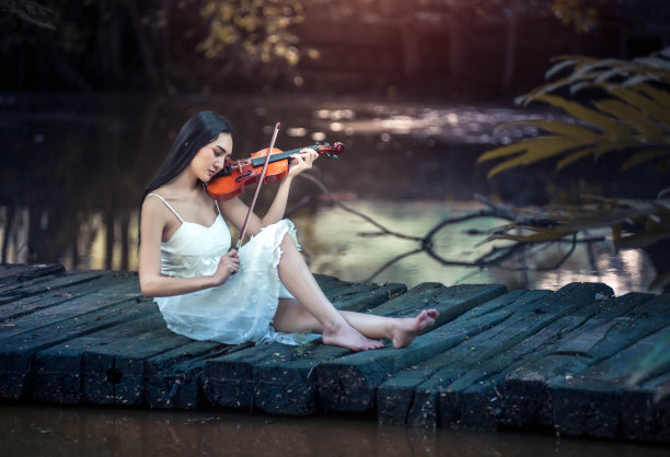 拉小提琴的漂亮姑娘。音乐家在公园里演奏音乐图片下载