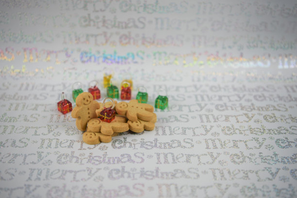 彩色的圣诞食品照片与圣诞树装饰的礼物礼物制成的彩色玻璃在红色绿色黄色与姜饼人饼干在节日的字白色银色包装纸图片下载