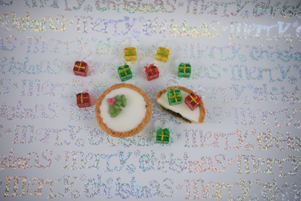 闪亮的彩色圣诞食品照片与圣诞树装饰的礼物礼物制成的彩色玻璃在红、绿、黄与冰肉馅饼在节日字白色银色包装纸图片下载