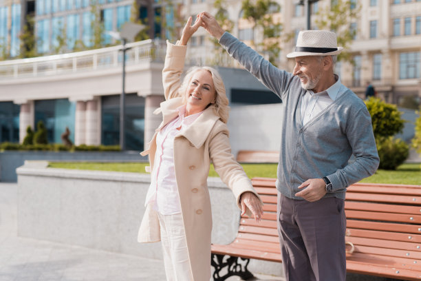 两个退休老人在长凳附近的广场上跳舞。他们很高兴图片下载