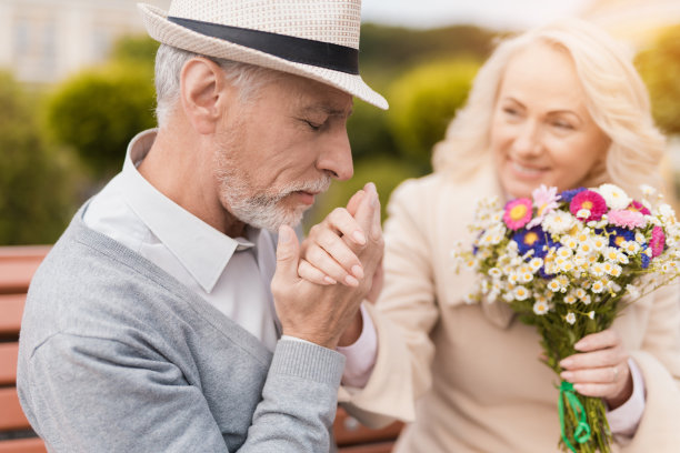 两个领养老金的人坐在巷子里的长凳上。一位上了年纪的男士轻轻地吻了一位女士的手图片下载